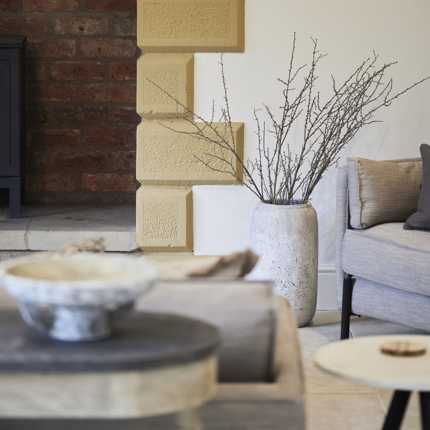 Distressed Stone Vase displayed in a modern living room, adding rustic charm to the interior decor.