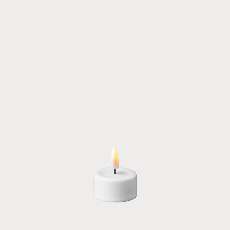 White LED Tealights placed in decorative holders on a dining table.
