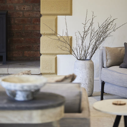 Distressed Stone Vase displayed in a modern living room, adding rustic charm to the interior decor.